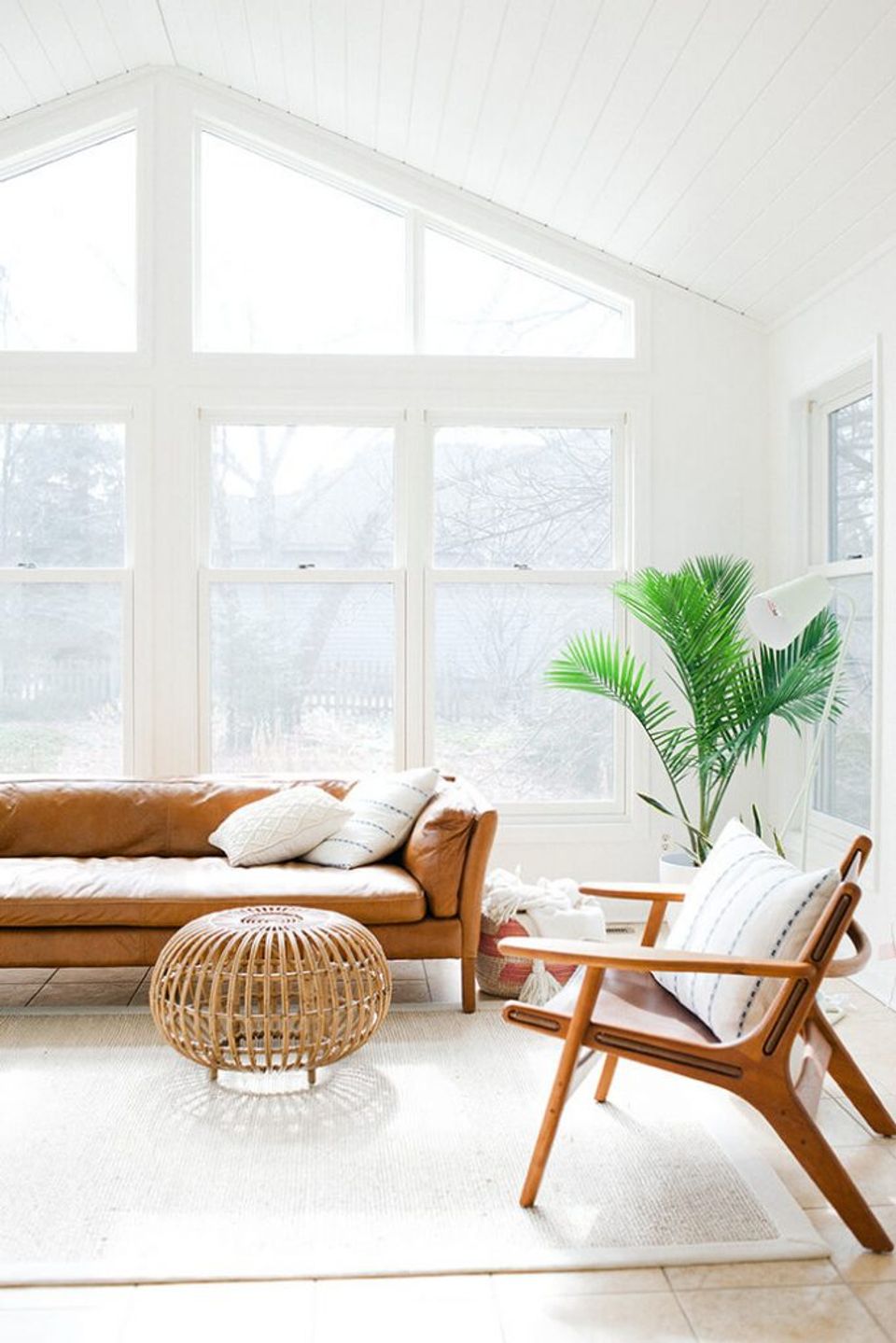 Scandinavian-inspired sunlit room with cognac leather sofa, woven accents, and abundant natural light