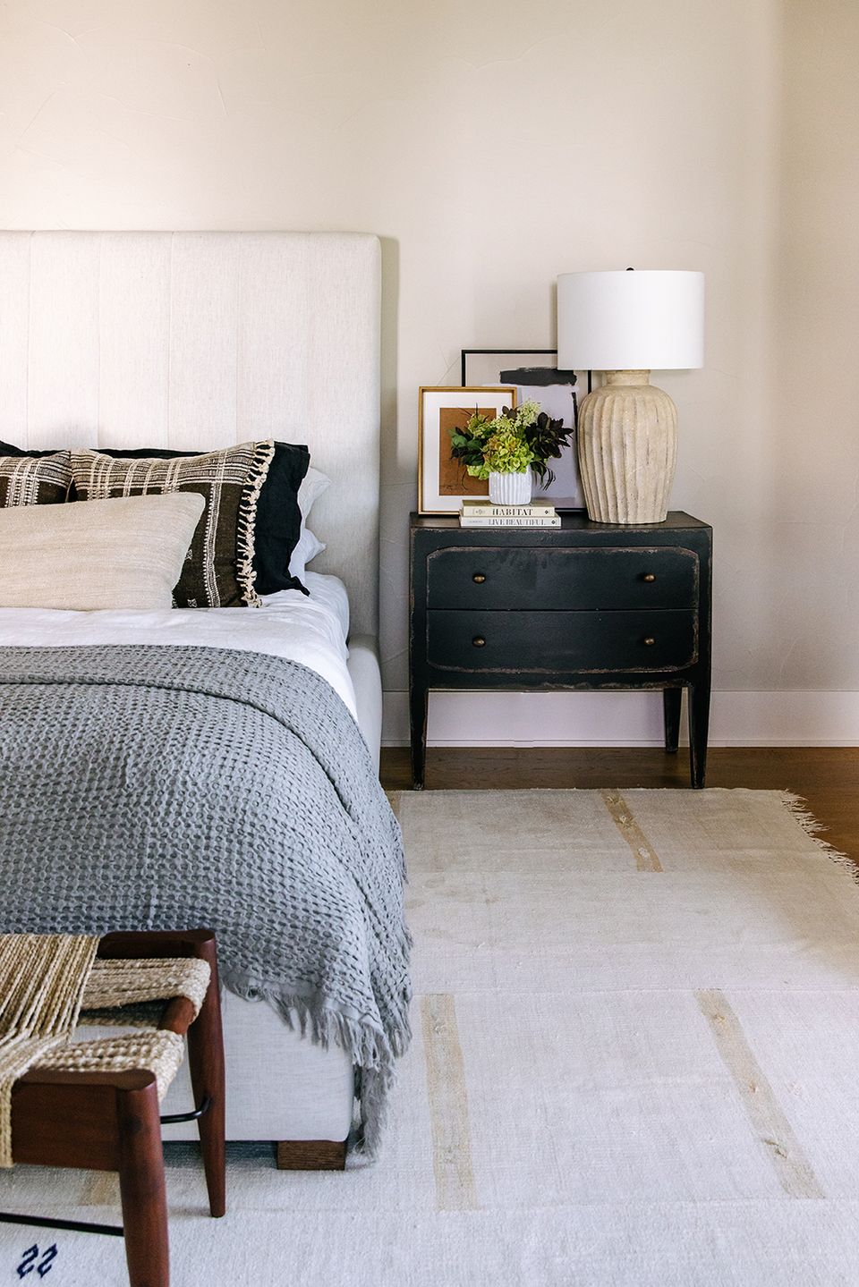 Serene organic modern bedroom with soft blue bedding, black nightstand, neutral tones, and textured accents
