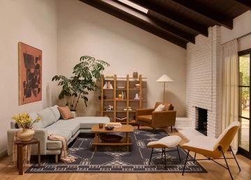Mid-century modern lounge with cream linen sectional, wood furniture, and warm layered lighting creating inviting ambiance.