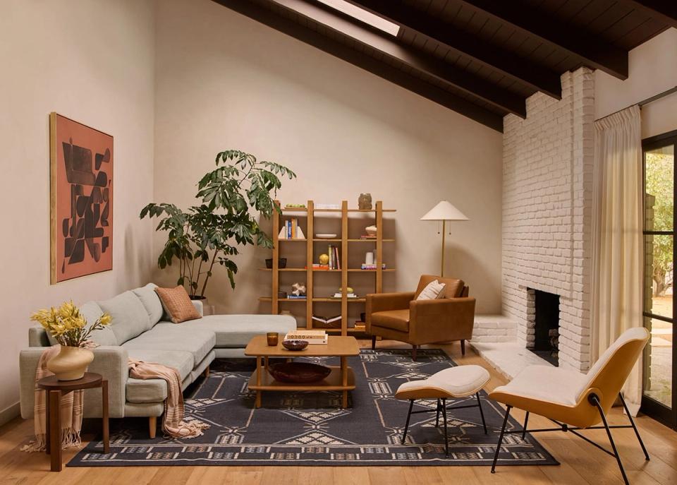 Mid-century modern lounge with cream linen sectional, wood furniture, and warm layered lighting creating inviting ambiance.