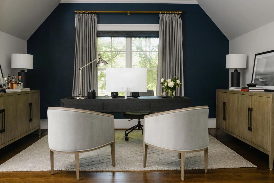 Contemporary workspace with dark accent wall, natural wood storage, and curved chairs