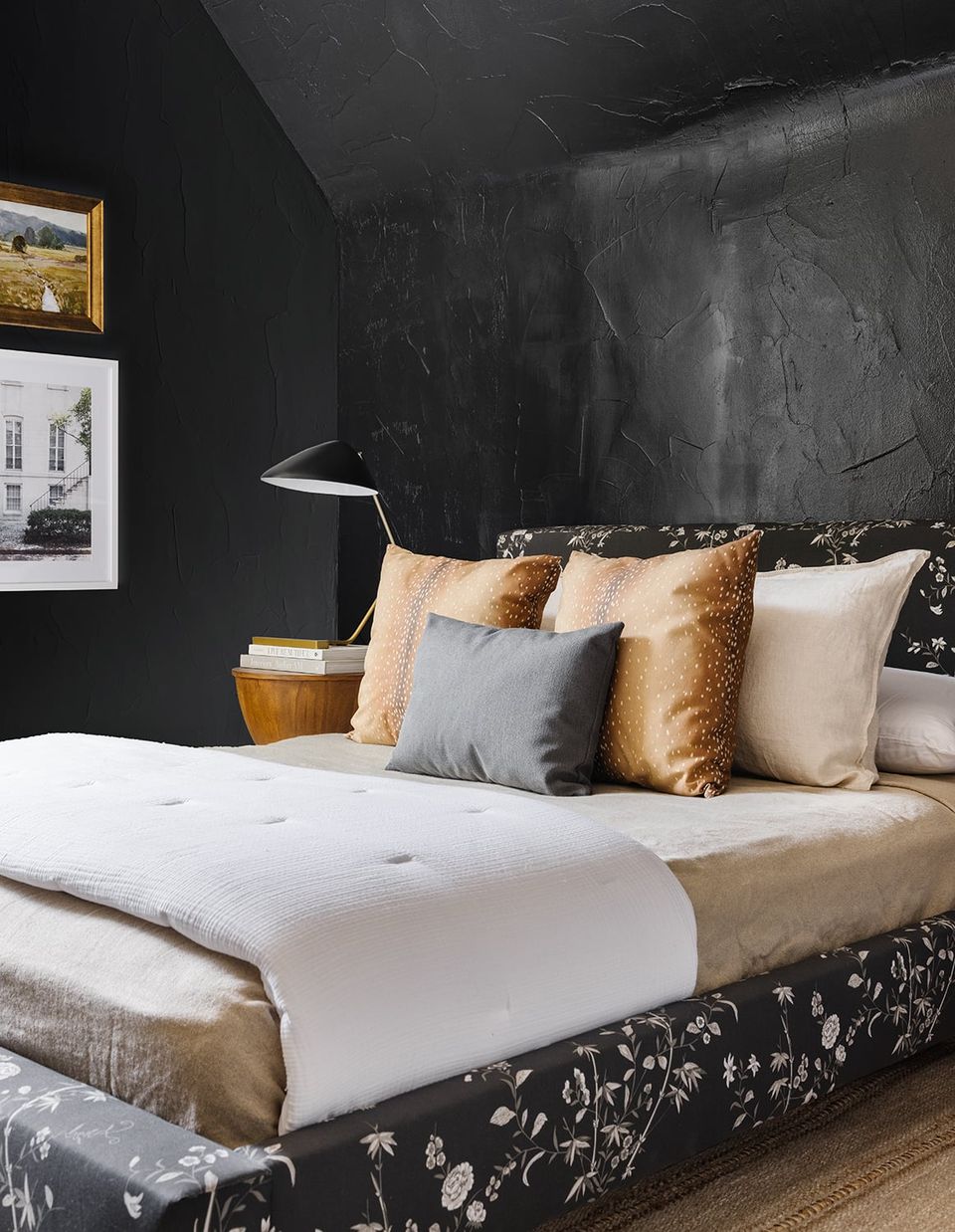 Luxe dark bedroom featuring black marble headboard, gold and cream pillows, and dramatic charcoal walls