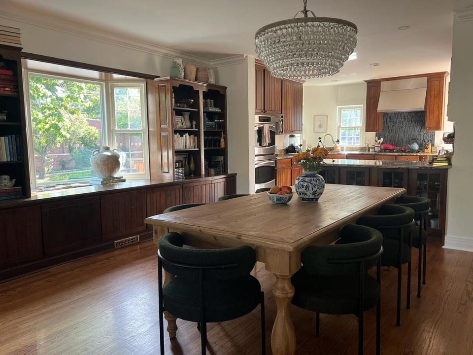 Warm transitional kitchen-dining space blending dark cabinetry, natural wood dining table, soft lighting, and cozy built-in window seating.