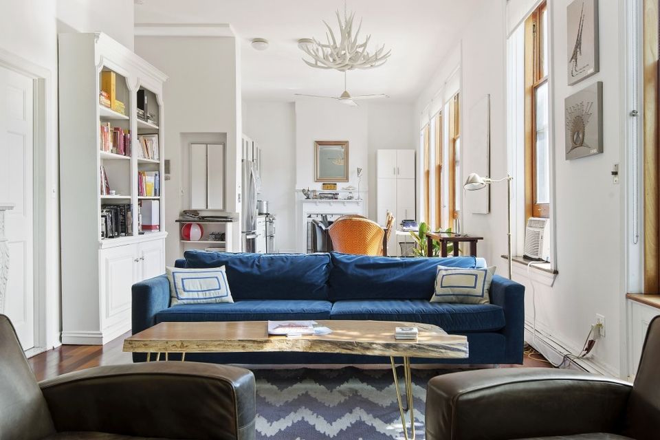 Bright contemporary living room with navy sofa, geometric rug, and abundant natural light from multiple windows