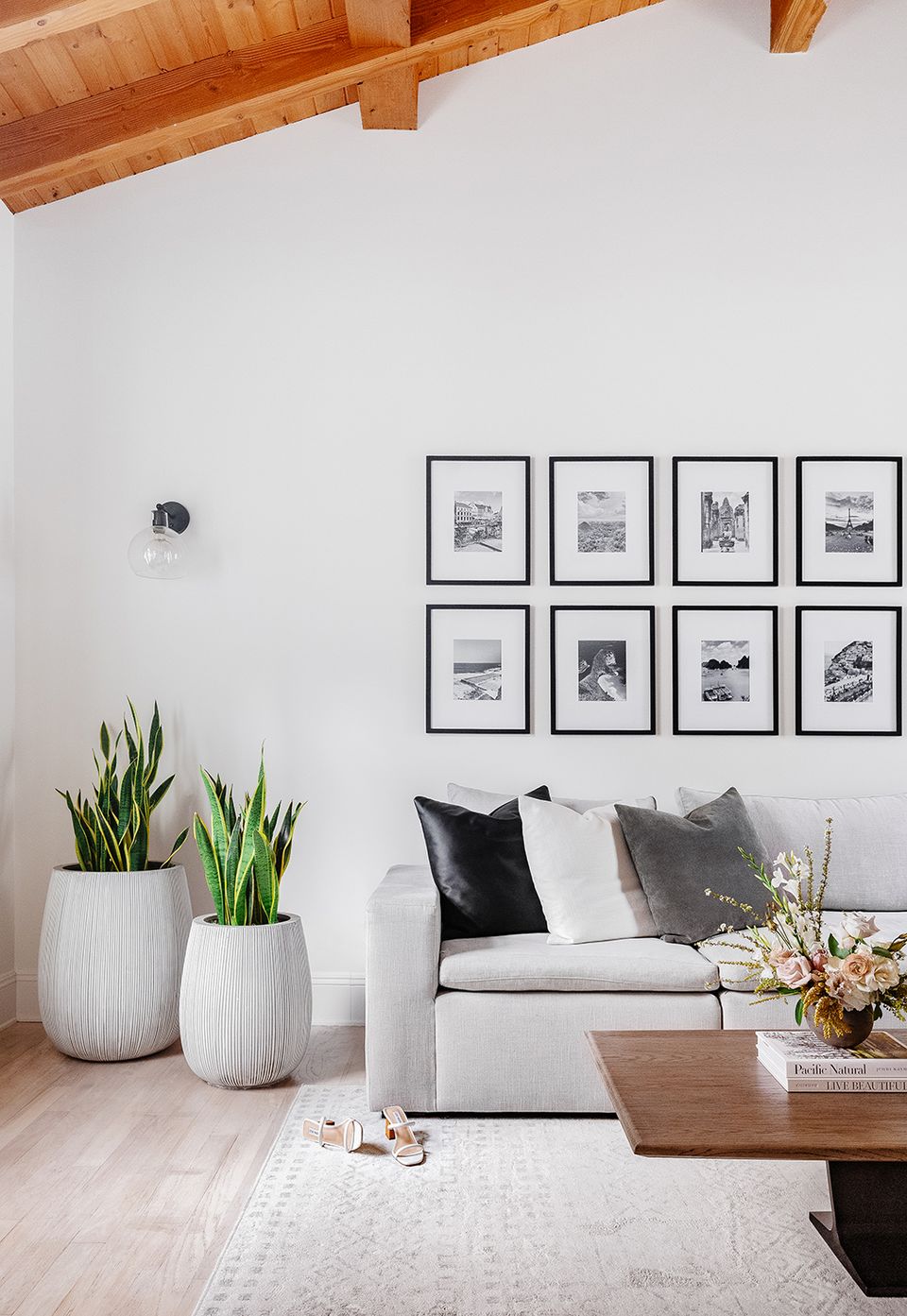 Clean minimalist aesthetic with light sofa, white planters, and gallery wall of black frames