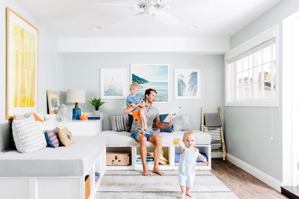 Bright, airy playroom with soft blue-gray walls, light wood flooring, and multifunctional storage blending modern comfort with family-friendly design.