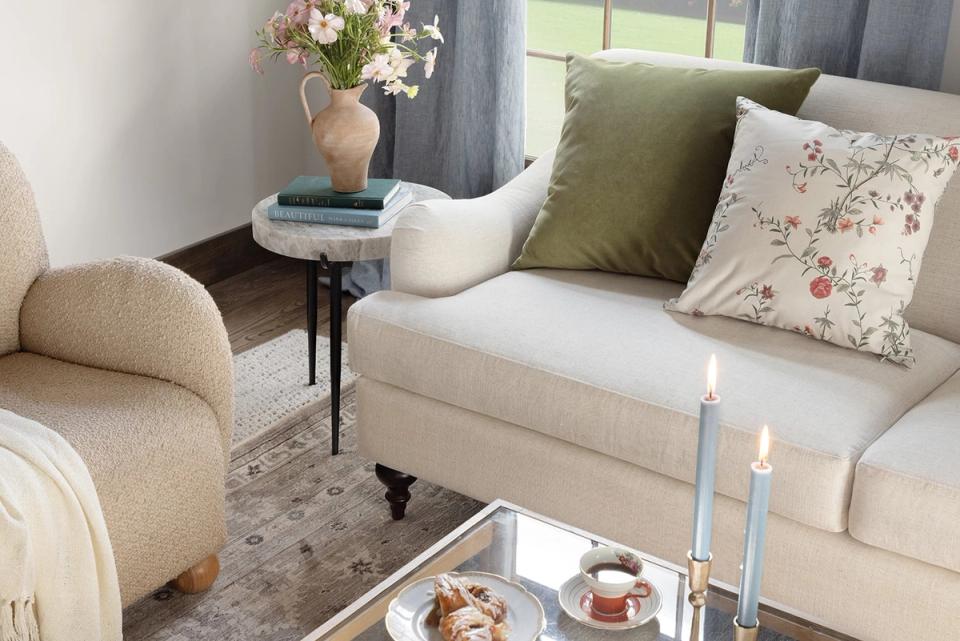 Cozy neutral seating nook with cream upholstery, sage green accents, and floral textiles