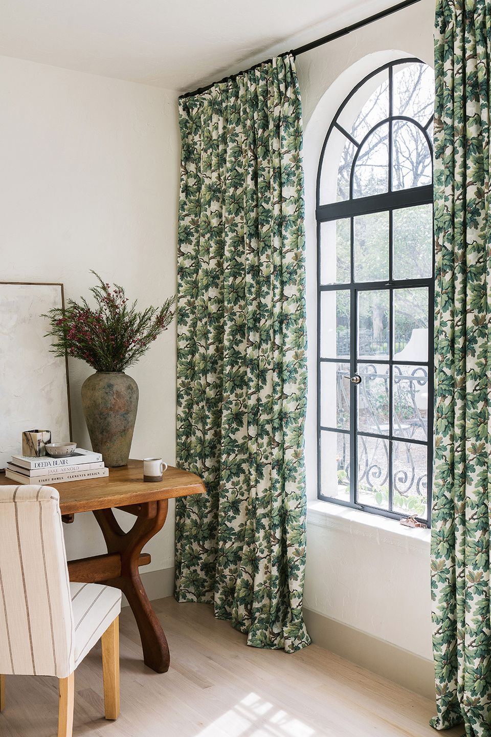 Botanical window treatment with green floral curtains and natural wood furnishings