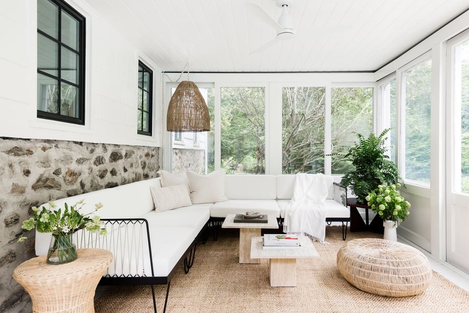 Bright Scandinavian sunroom with white sectional, natural textures, and abundant greenery