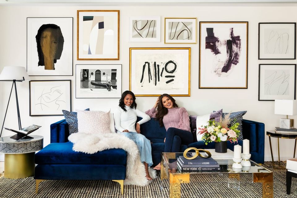 Modern gallery wall with abstract art above a plush blue velvet sofa, creating a chic, contemporary living room aesthetic.