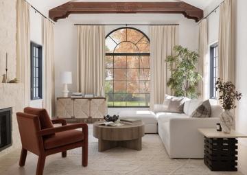 Modern farmhouse living room blending rust leather chair, cream sofa, natural wood elements, and botanical accents