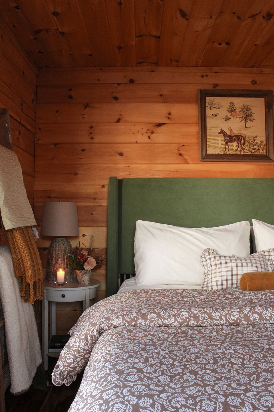 Rustic cabin bedroom with knotty pine walls and forest green upholstered headboard