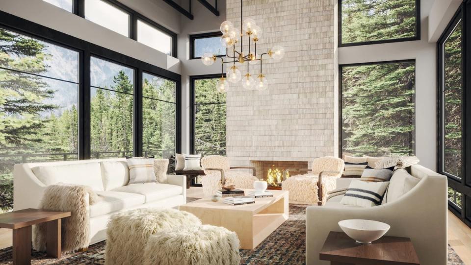 Bright alpine living room with cream sectional, natural wood accents, and forest views through black-framed windows