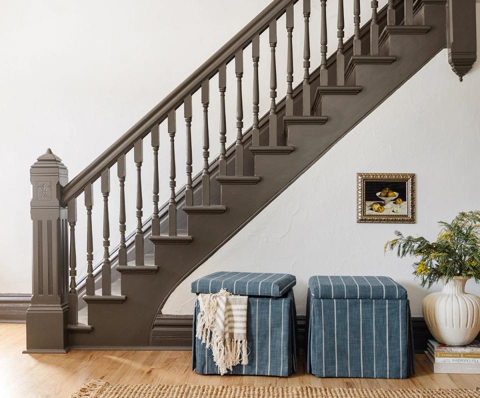 Coastal entryway with striped blue ottomans beneath staircase and woven accents