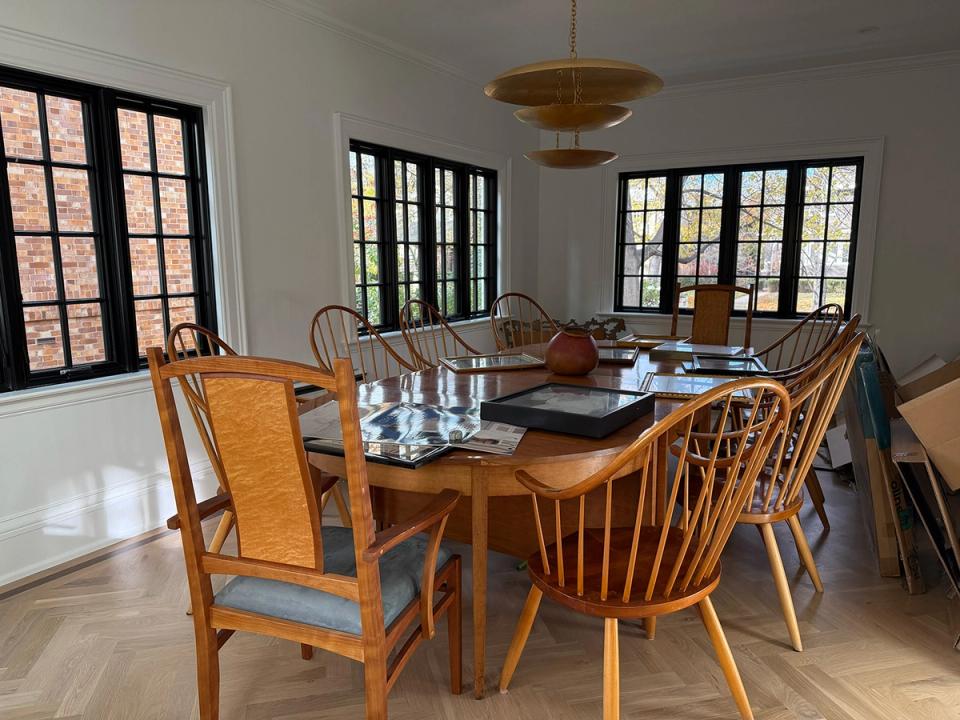 Mid-century modern dining room with warm wood table, Windsor chairs, and natural light from black-framed windows