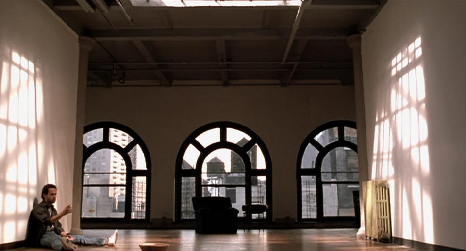 Dramatic industrial loft with arched windows, soaring ceilings, and refined minimalist composition