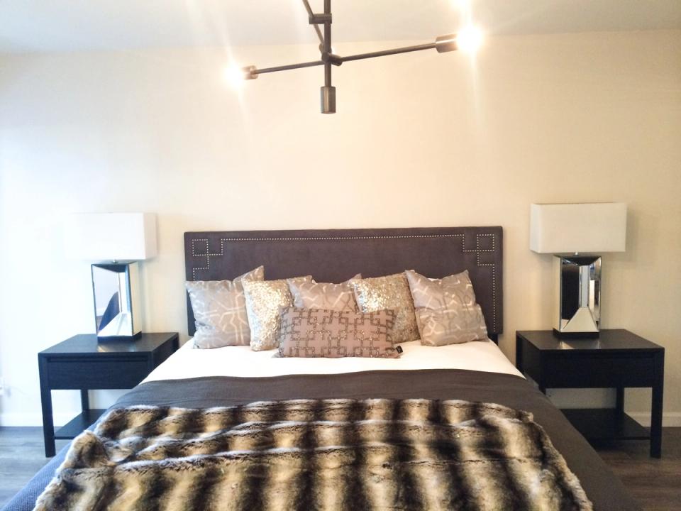 Contemporary bedroom with dark headboard, geometric bedding, and modern brass ceiling fixture