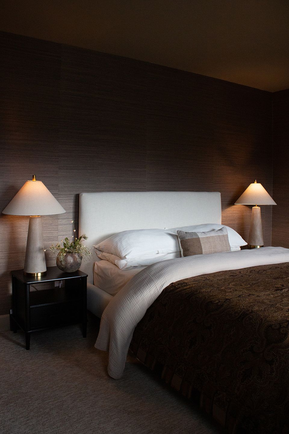 Sophisticated bedroom with dark brick walls, warm lighting, and neutral tones