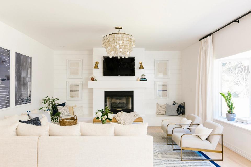 Bright minimalist living room with white fireplace, cream furniture, and modern pendant lighting