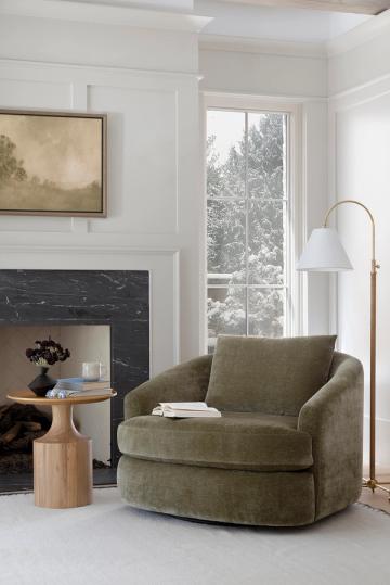 Modern classic living room with sage green rounded chair, fireplace surround, and soft taupe color scheme.