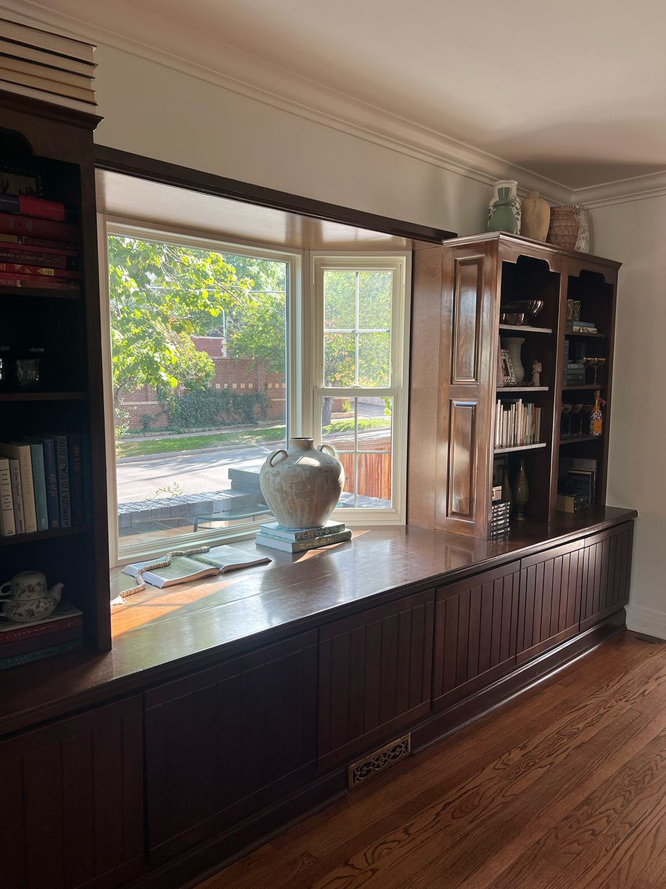 Serene kitchen workspace with dark wood built-ins, open shelving, and abundant natural light from windows