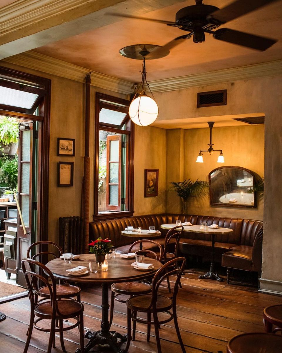 Warm rustic-modern dining room with golden walls, leather seating, and vintage wood furnishings
