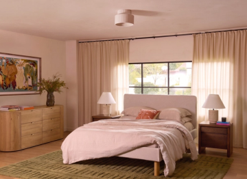 Bedroom with a wood dresser, upholstered bed, and green striped bedding