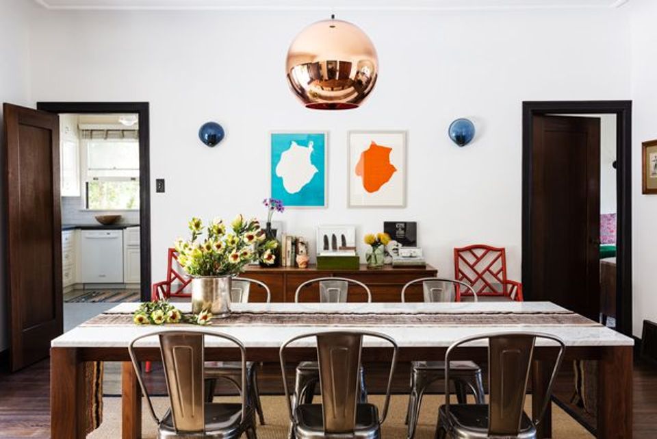 Mid-century dining space with bold colorful art, copper pendant light, and warm wood furnishings