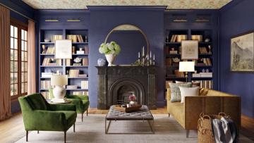Rich jewel-tone blue sitting room with dark fireplace, built-in shelving, emerald velvet chair, and brass accents