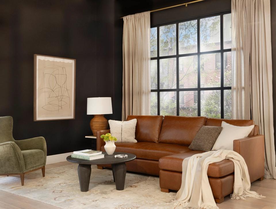 Modern living room with cognac leather sectional, dark accent wall, and warm neutral tones