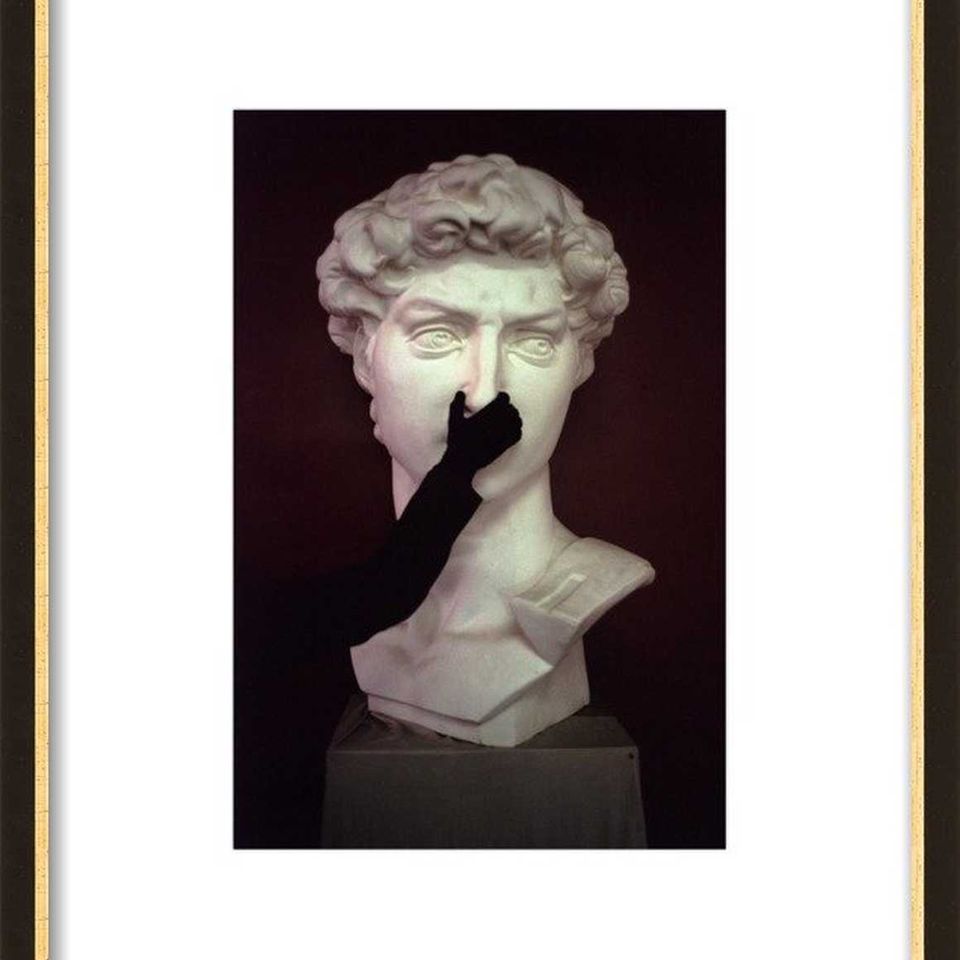 Minimalist classical bust sculpture with dramatic dark background and gold frame creating sophisticated artistic statement