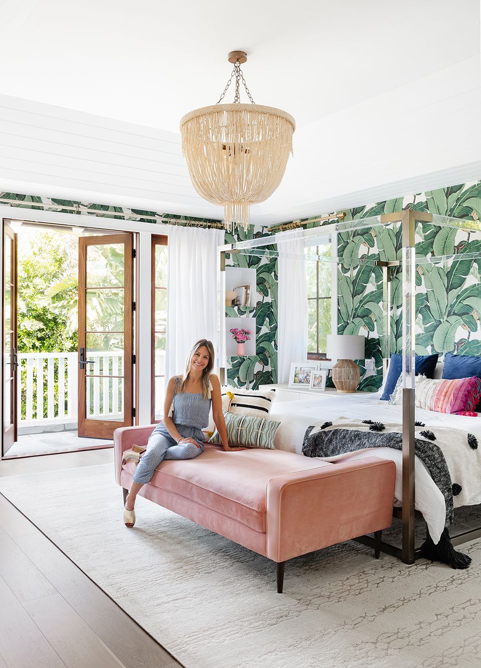 Tropical bedroom with botanical wallpaper, coral upholstered bench, and natural woven ceiling fixture
