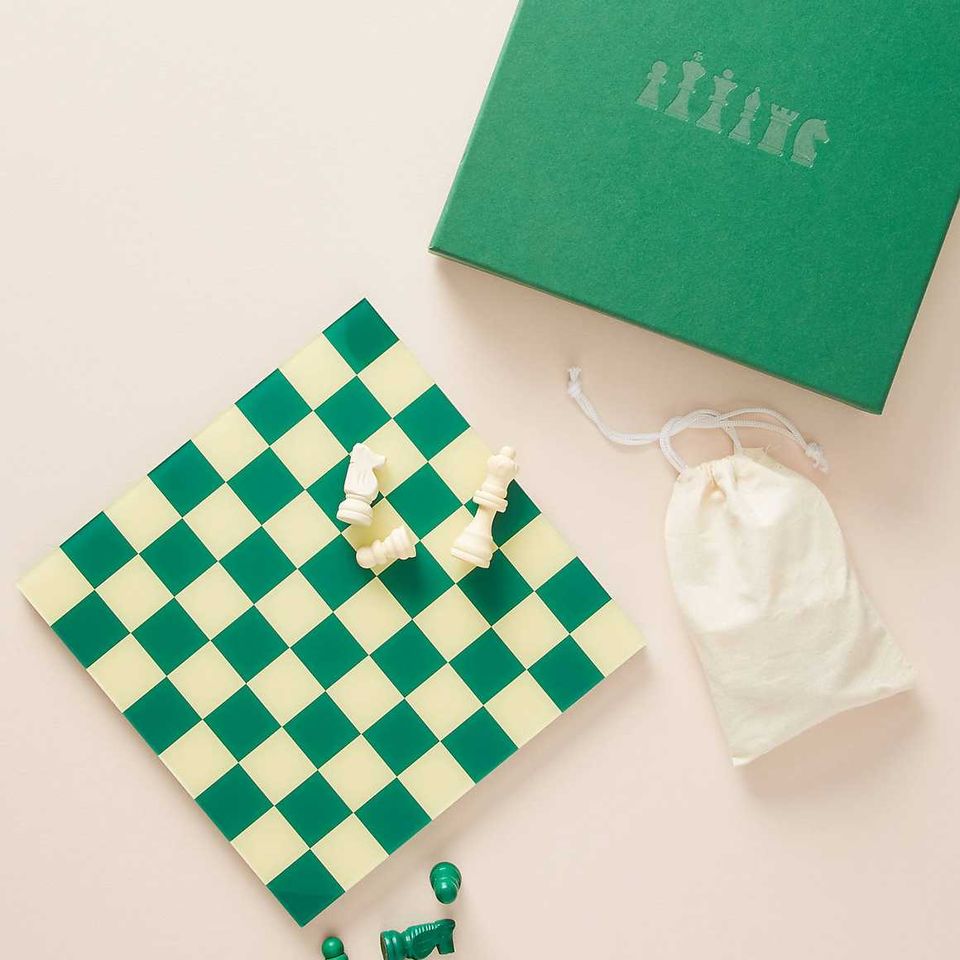 Elegant game night setup with emerald green checkerboard, brass chess pieces, and cream neutral backdrop