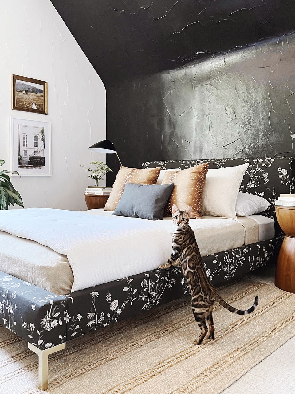 Modern bedroom with black marble accent wall and botanical patterned upholstered bed