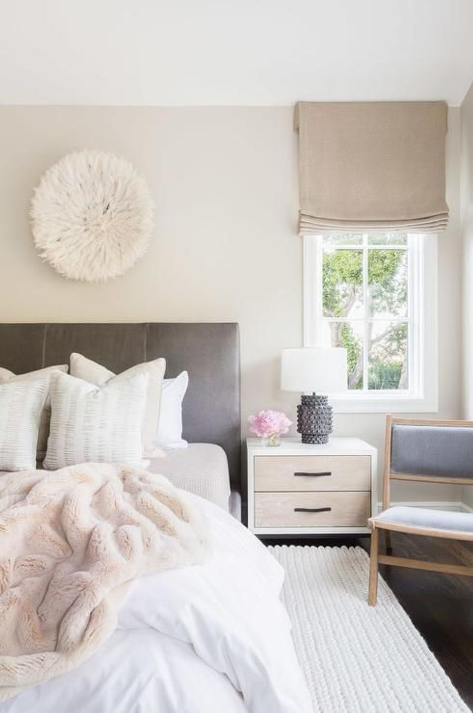 Serene neutral bedroom with soft pink bedding, textured wall art, and natural light