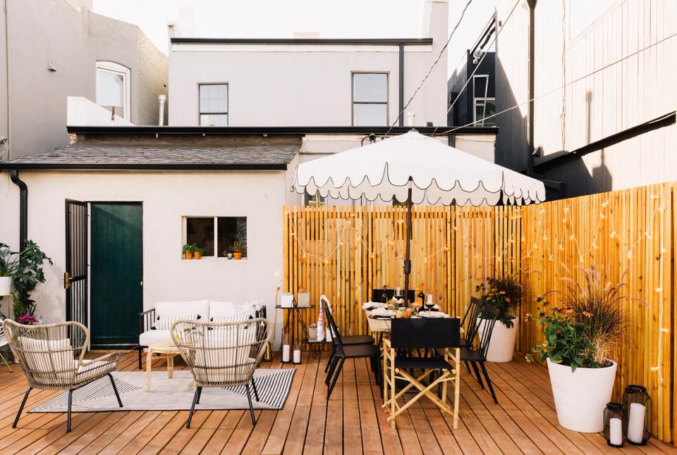 Modern minimalist deck with warm wood tones, mid-century wire chairs, striped awning, and clean Scandinavian aesthetic.
