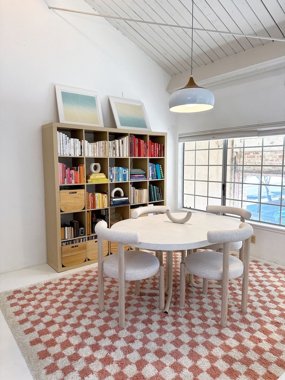 Bright Scandinavian workspace with natural wood shelving, geometric patterned rug, and round dining table