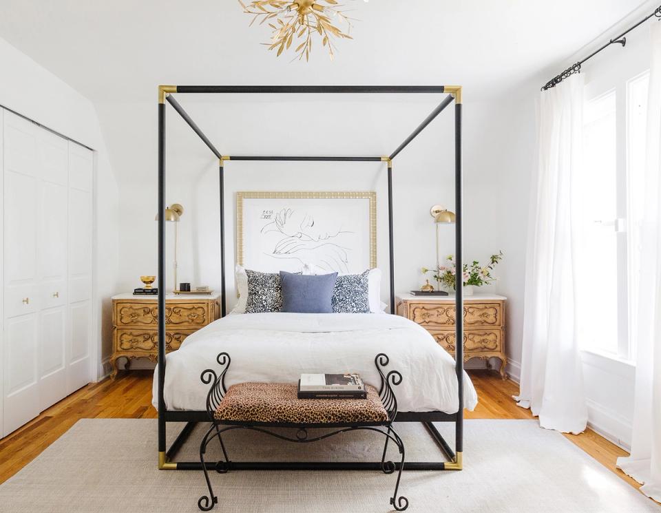 Modern farmhouse bedroom with black canopy bed, natural wood nightstands, and soft neutral palette