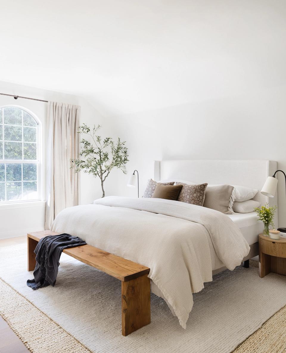 Serene Scandinavian guest room with cream linens, wooden bench, and soft neutral palette
