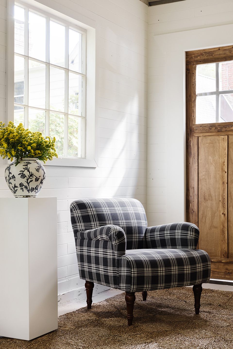 Bright farmhouse entry with shiplap, black plaid chair, and natural light—classic but transitional style