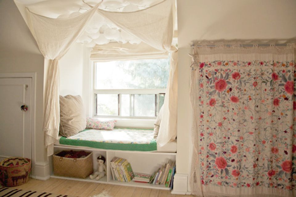 Cozy cottage bedroom nook with sheer curtains, floral fabric, and built-in window seat storage