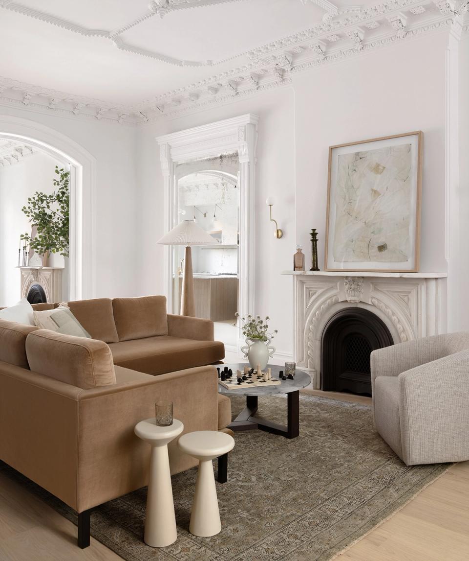 Bright transitional living room blending caramel and cream seating with fireplace and ornate ceiling detail