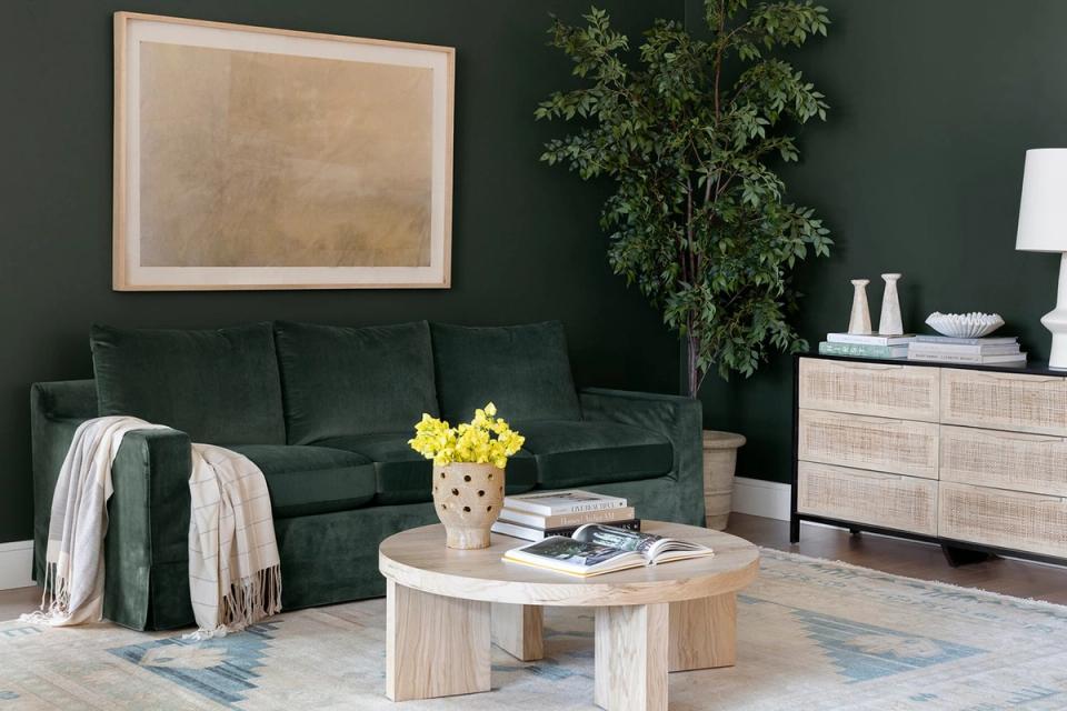 Sophisticated living room with deep forest-green sofa, natural wood, and minimalist styling