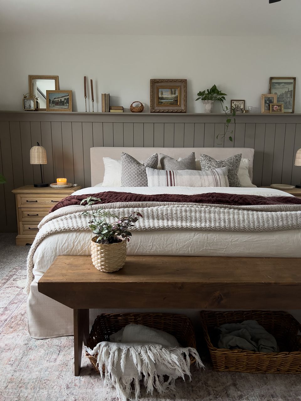 Farmhouse bedroom with sage green shiplap accent wall, neutral bedding, and rustic wood bench