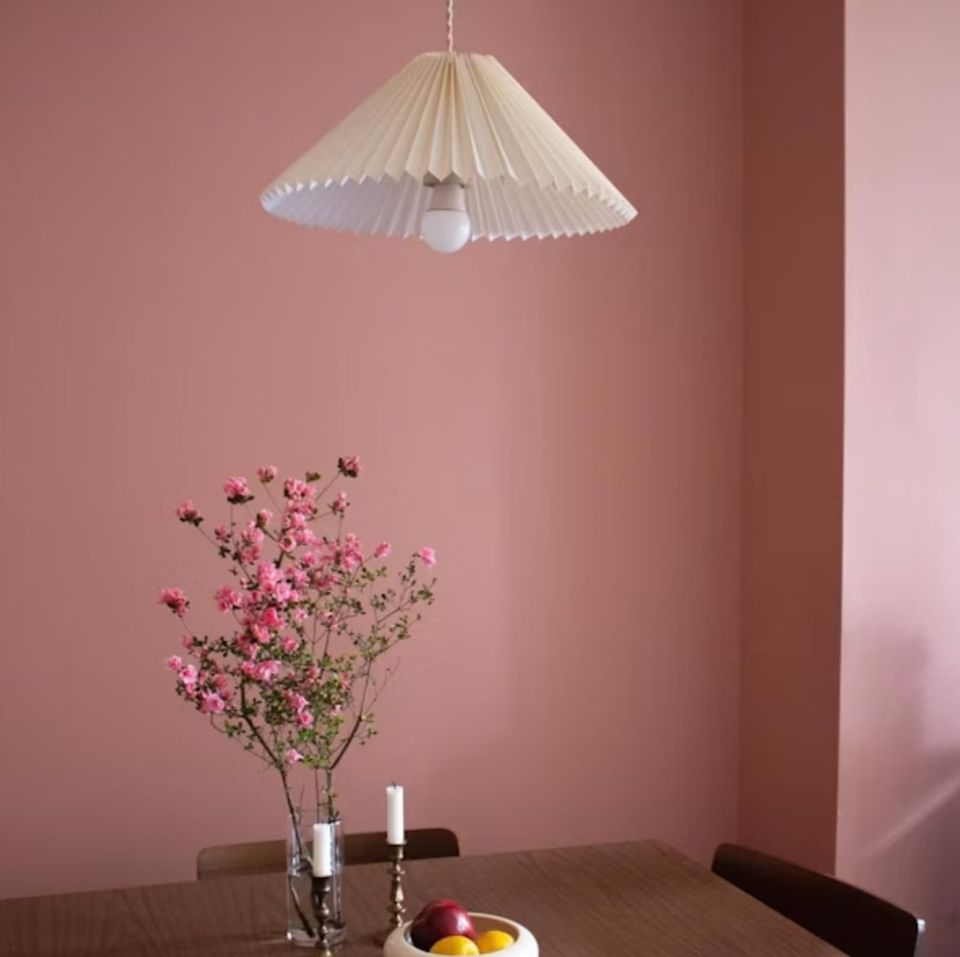 Warm dusty pink dining space with minimalist white pendant light and delicate pink baby's breath flowers in vase