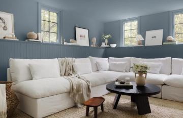 Modern living room with slate blue accent wall, cream sectional, and minimalist wooden accents