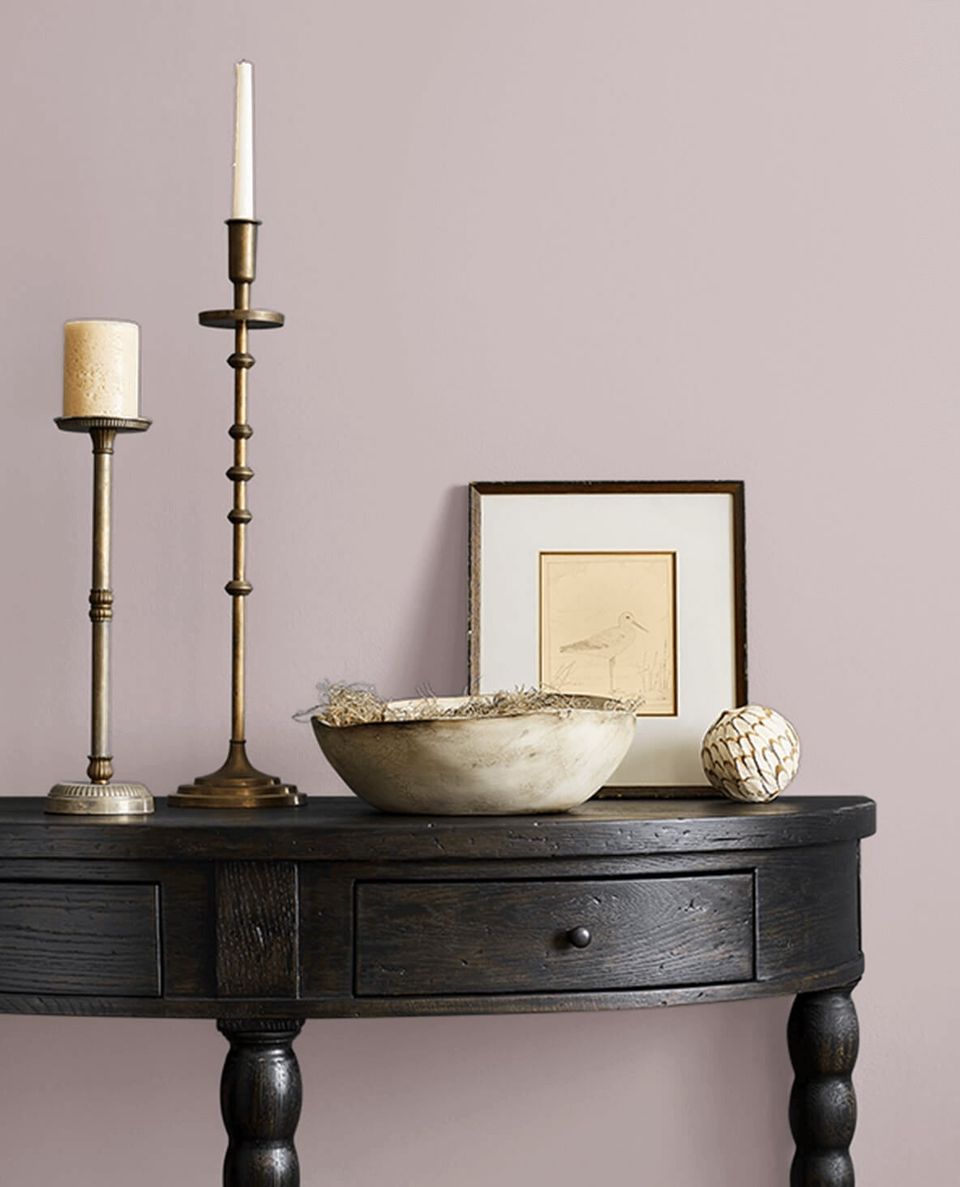 Sophisticated mauve accent wall with dark console table, brass candlesticks, and curated décor creating understated, transitional glamour.