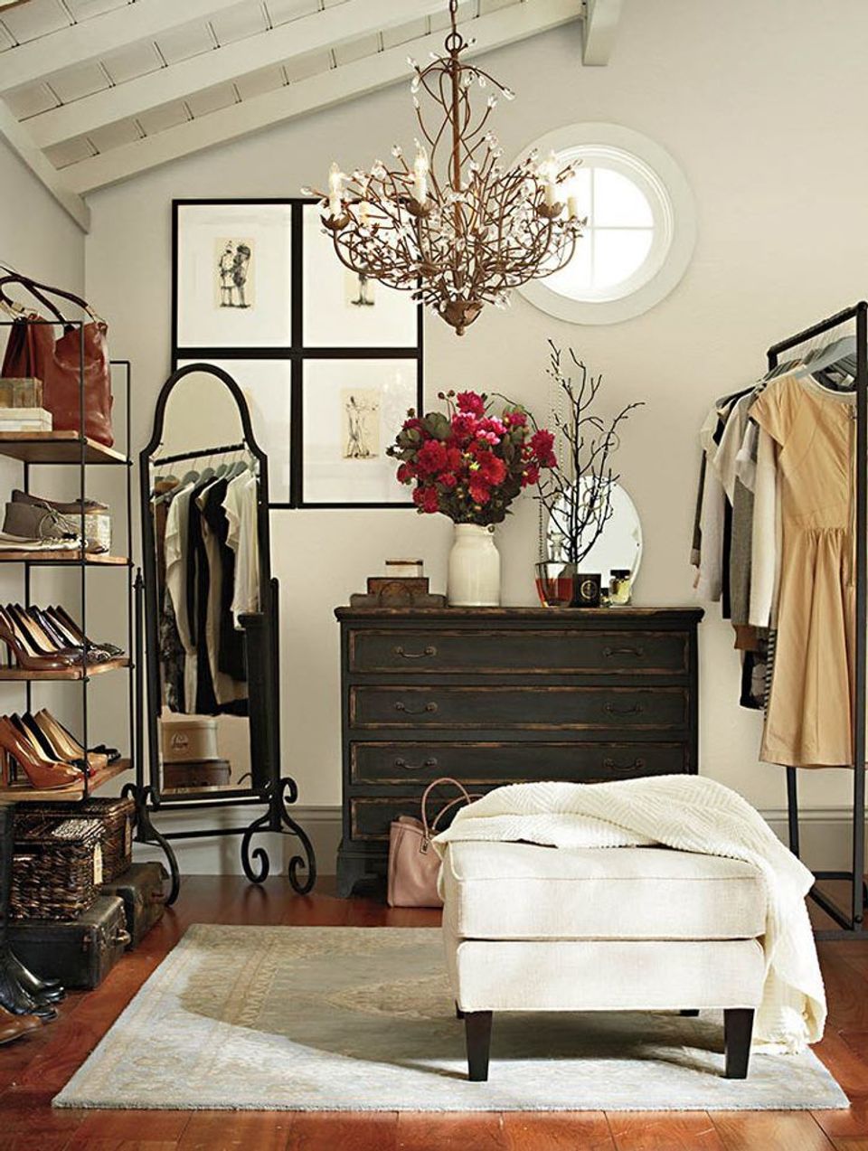Eclectic bedroom gallery wall with black frames above dark dresser, chandelier, and burgundy floral arrangement