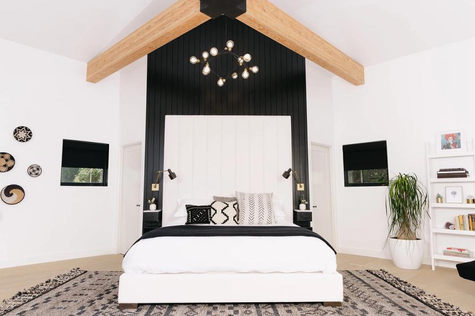 Modern minimal bedroom with geometric black headboard accent, natural wood frame, and airy white palette