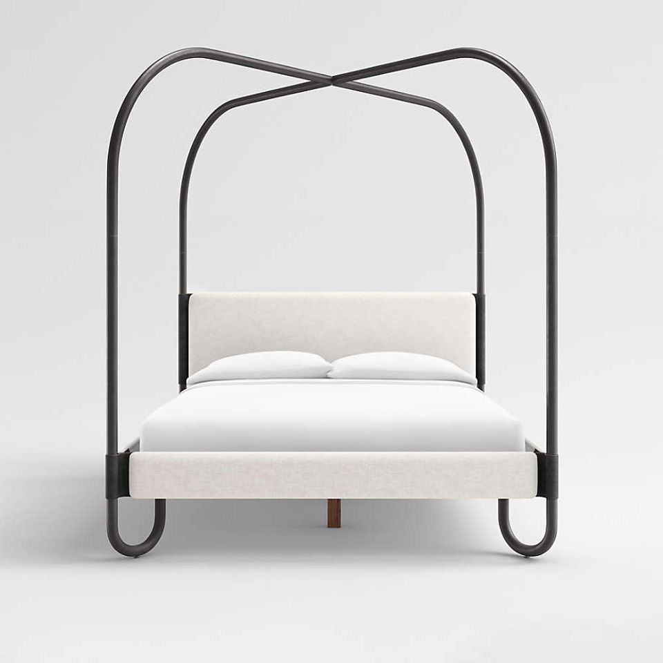 Contemporary minimalist canopy bed with curved black metal frame and cream upholstered headboard